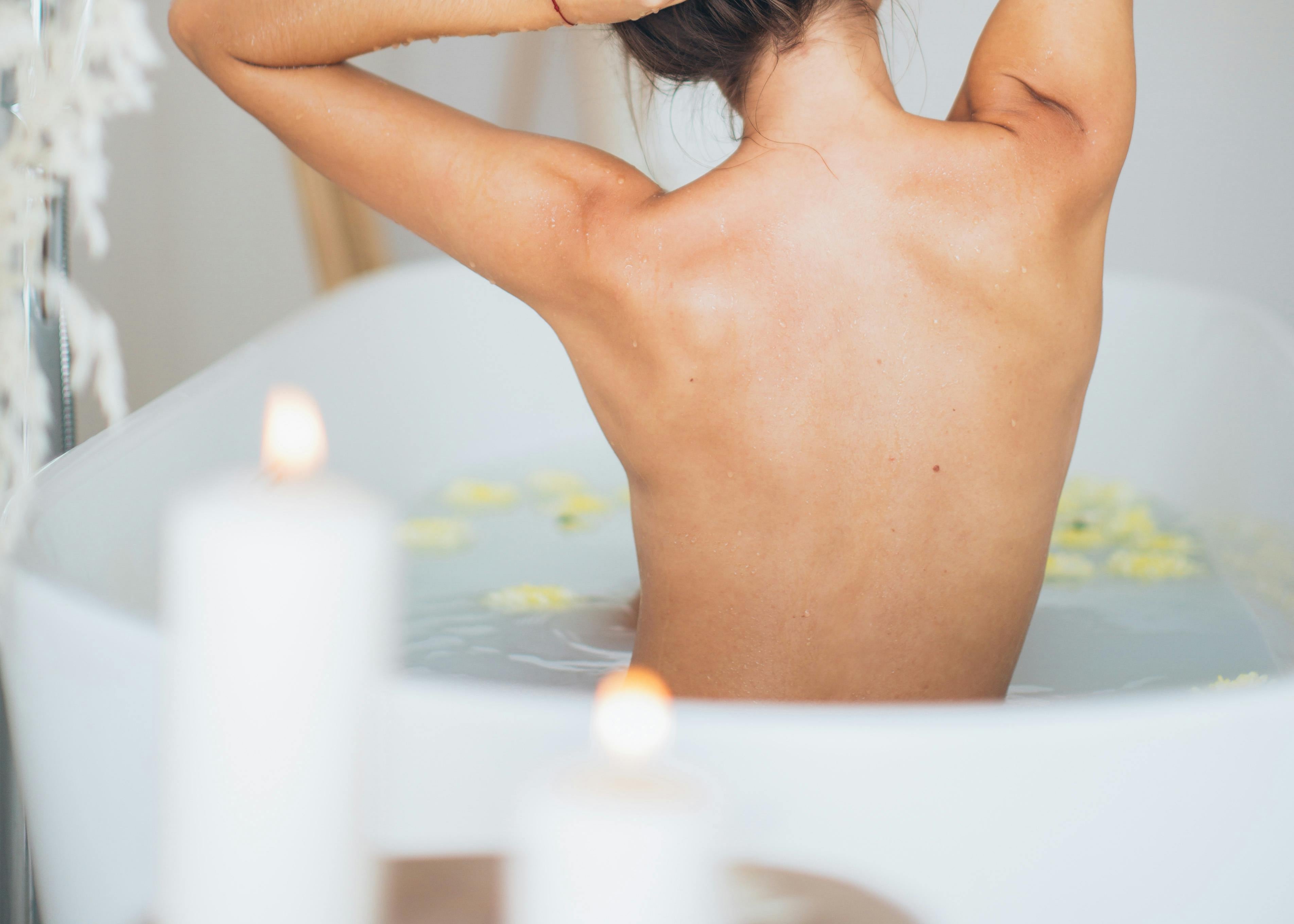 Chill vibe – woman relaxing in a floral bath with soft candlelight ambiance.