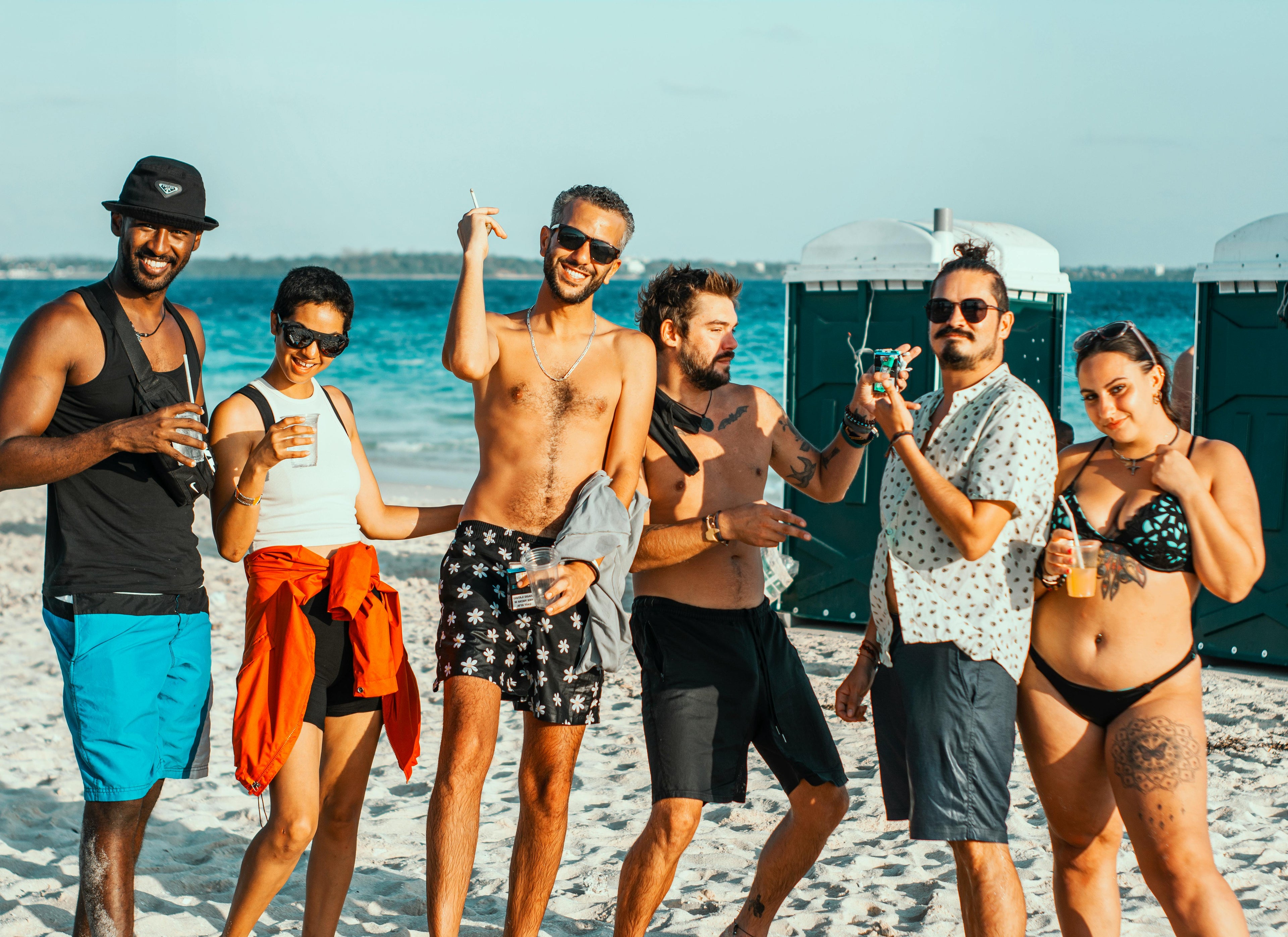 Group of friends enjoying a sunny beach day in stylish swimwear and sunglasses, capturing the carefree, social spirit of VLIZ summer lifestyle.