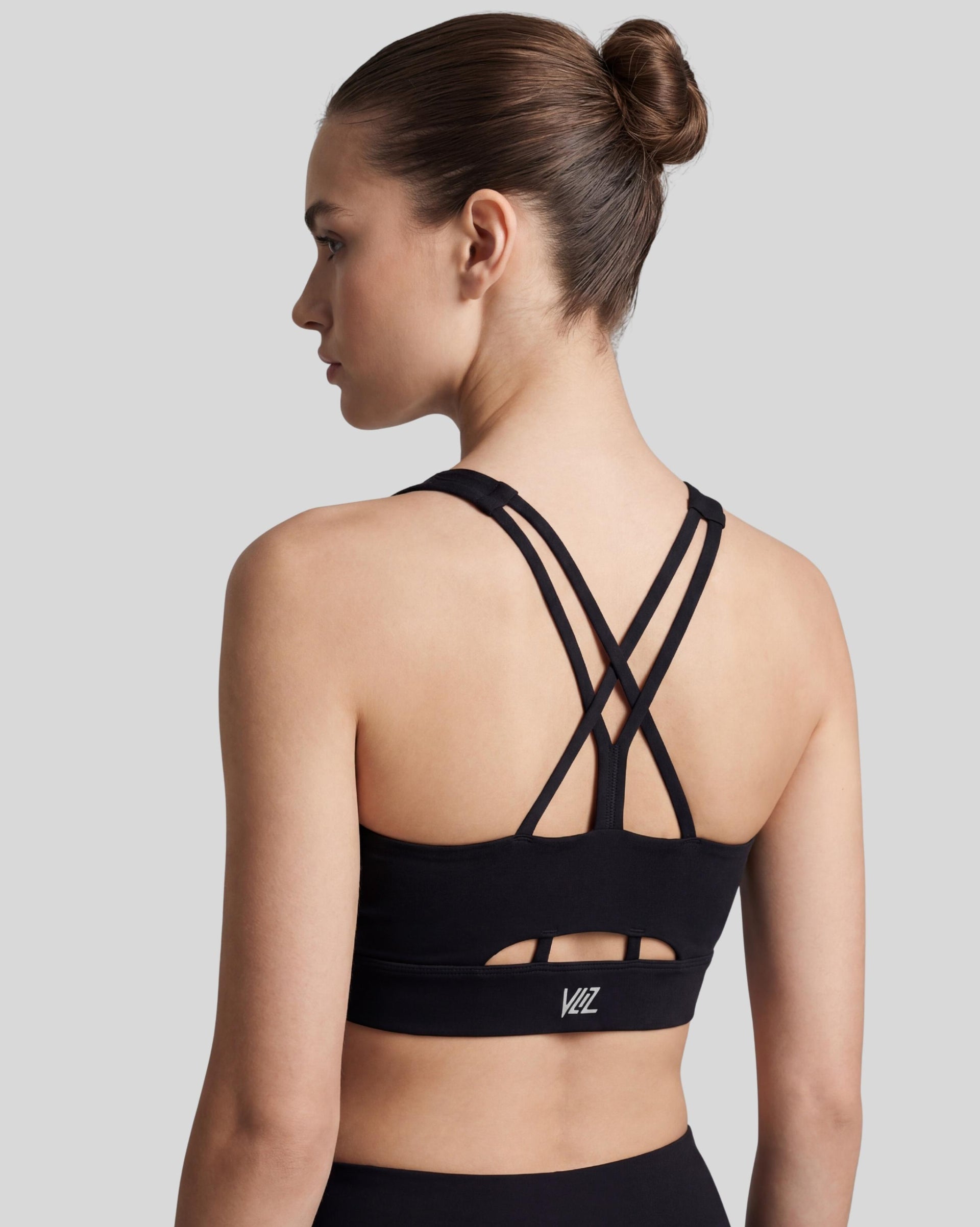 VLIZ AuraFlow Cross-Back Sports Bra, black, with smooth fabric and a supportive fit. The design features elegant double cross-back straps and a discreet keyhole detail below the straps. Ideal for gym workouts, yoga, Pilates, and everyday training.
