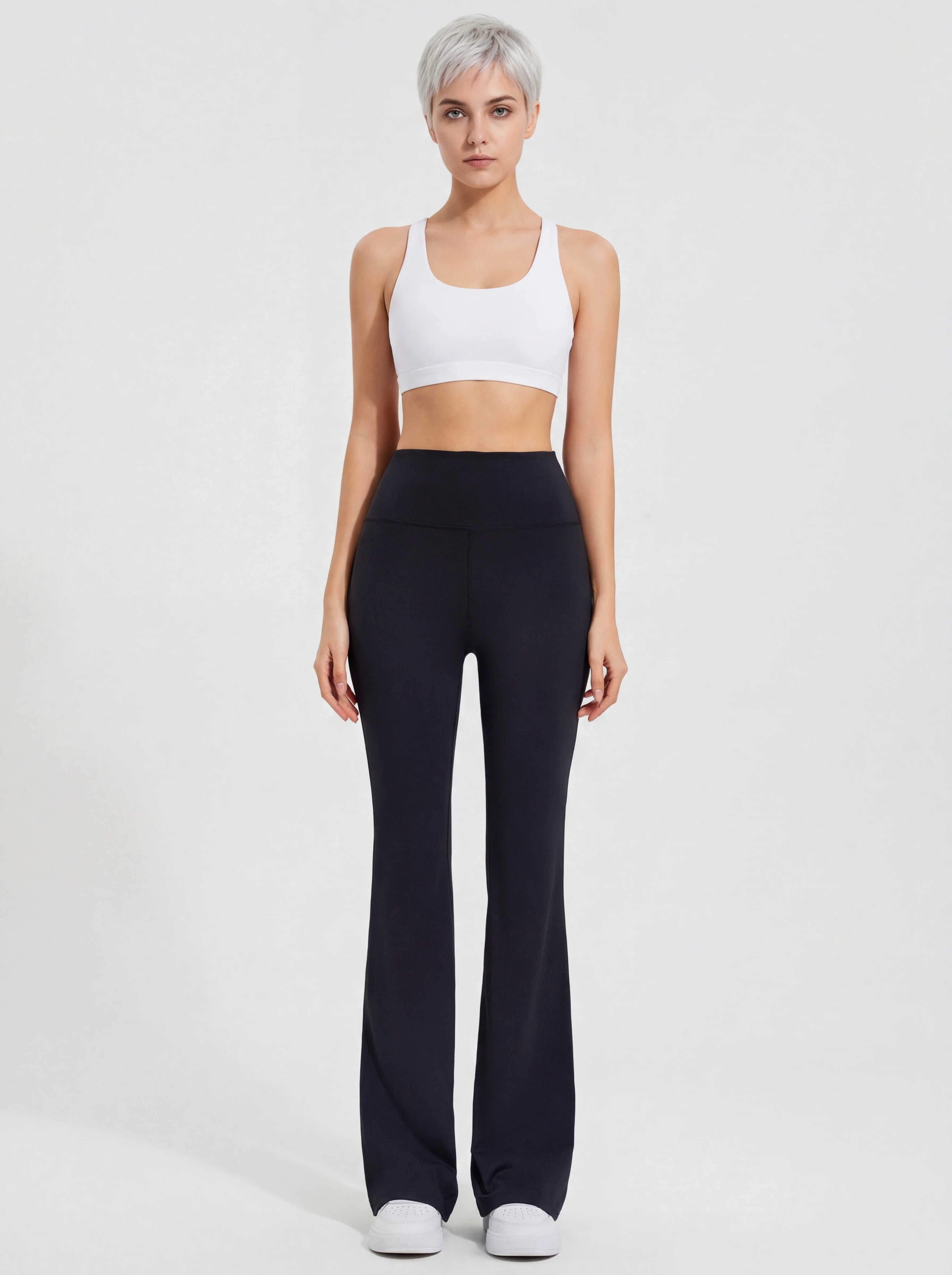 Woman wearing a white tank top and black high-waisted pants on a light gray background
