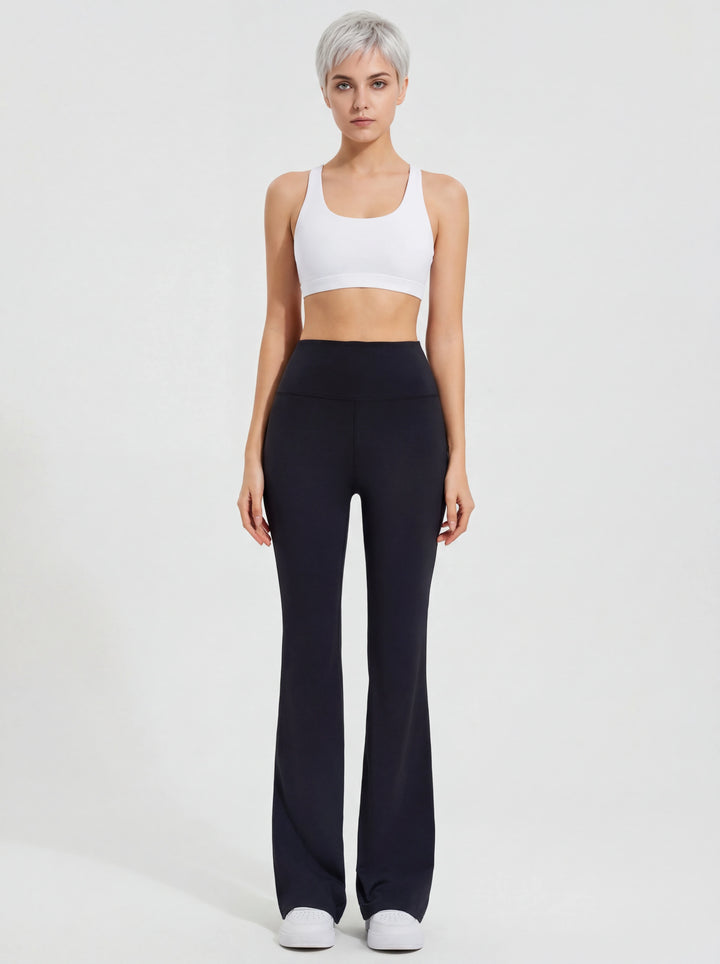 Woman wearing a white tank top and black high-waisted pants on a light gray background