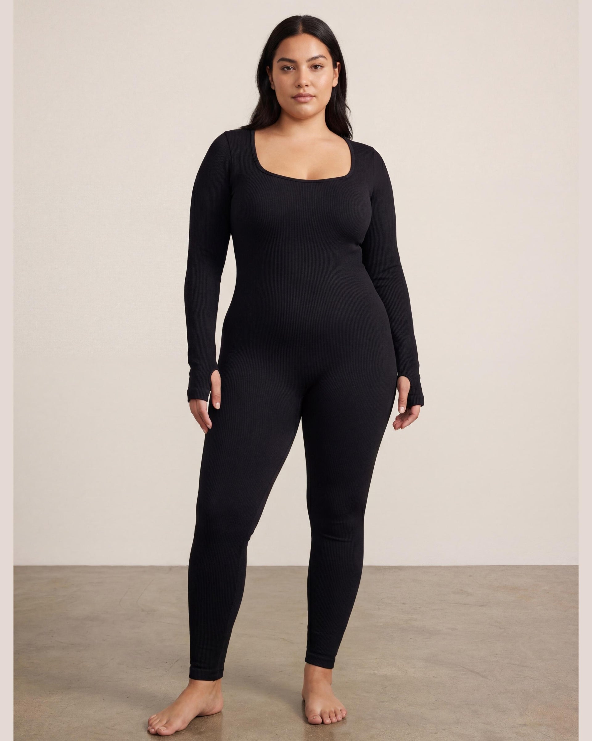 VLIZ Eclipse Ribbed Sculpting Jumpsuit; A female model showcases the full-length black activewear jumpsuit, featuring a form-fitting ribbed fabric, a square neckline, and long sleeves with thumbholes. It offers a supportive fit, suitable for gym workouts, yoga, Pilates, and everyday training.