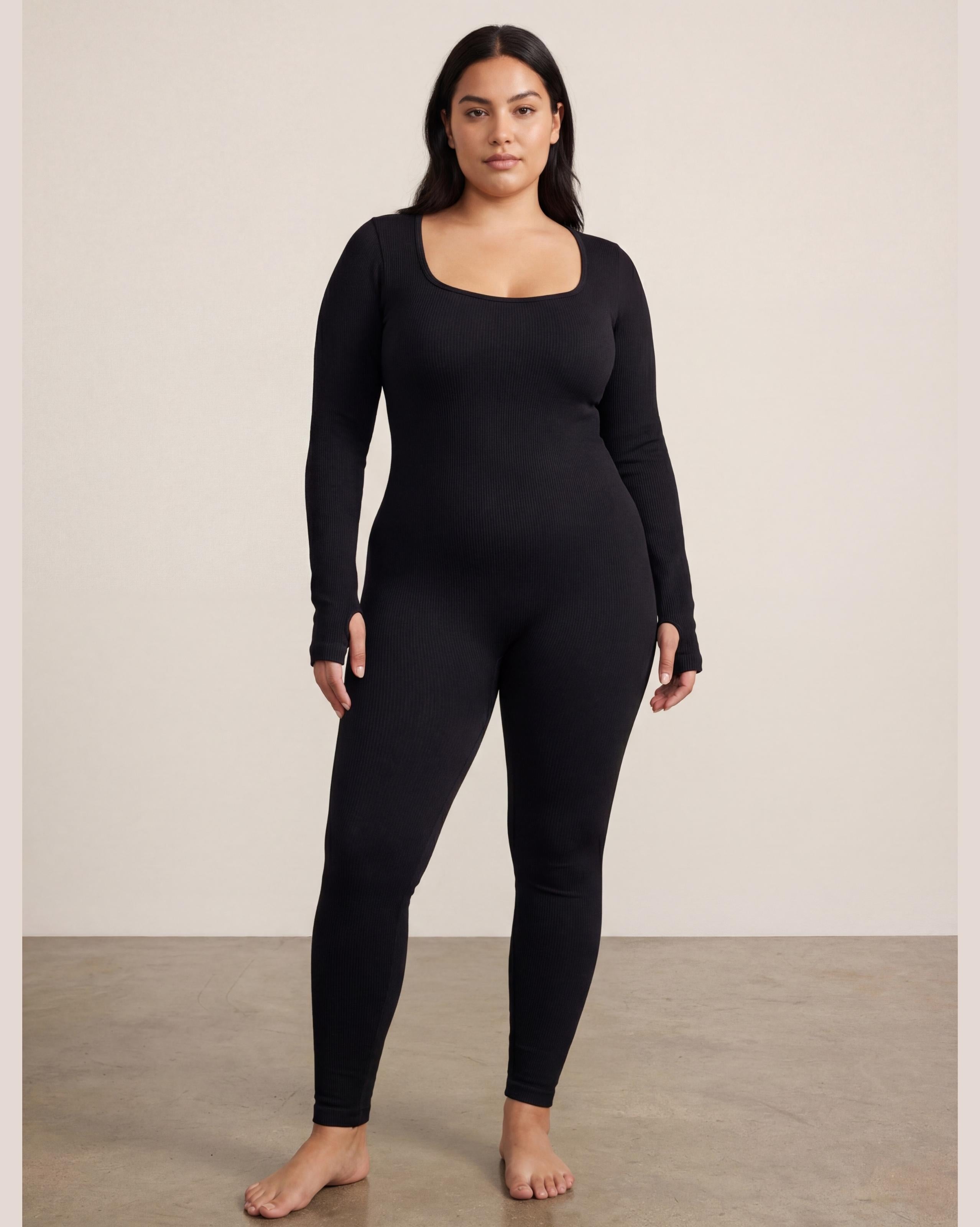 VLIZ Eclipse Ribbed Sculpting Jumpsuit; A female model showcases the full-length black activewear jumpsuit, featuring a form-fitting ribbed fabric, a square neckline, and long sleeves with thumbholes. It offers a supportive fit, suitable for gym workouts, yoga, Pilates, and everyday training.