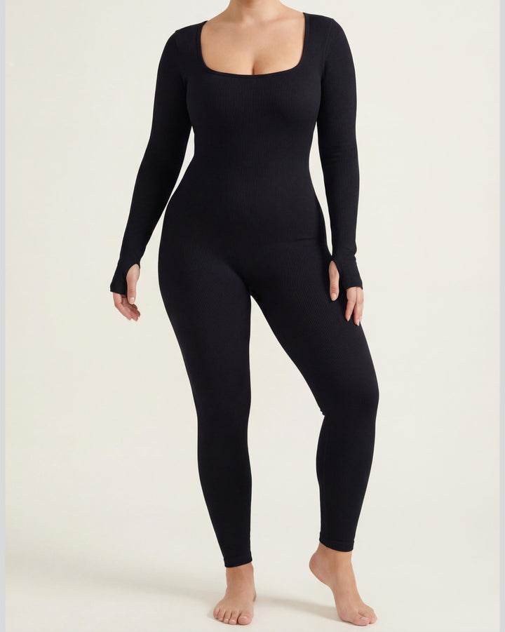 VLIZ Eclipse Ribbed Sculpting Jumpsuit; A female model showcases the full-length black activewear jumpsuit, featuring a form-fitting ribbed fabric, a square neckline, and long sleeves with thumbholes. It offers a supportive fit, suitable for gym workouts, yoga, Pilates, and everyday training.