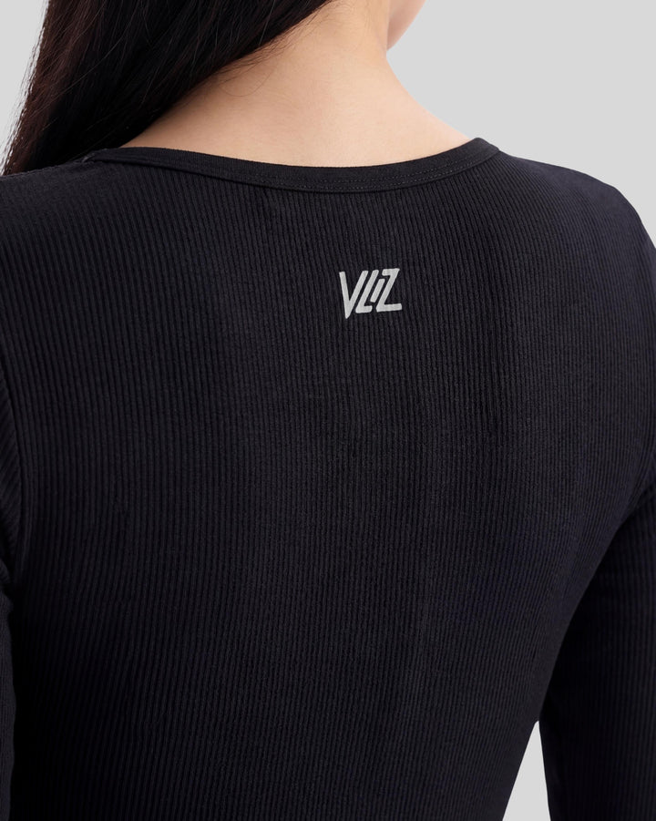 VLIZ Eclipse Ribbed Sculpting Jumpsuit; A female model showcases the full-length black activewear jumpsuit, featuring a form-fitting ribbed fabric, a square neckline, and long sleeves with thumbholes. It offers a supportive fit, suitable for gym workouts, yoga, Pilates, and everyday training.