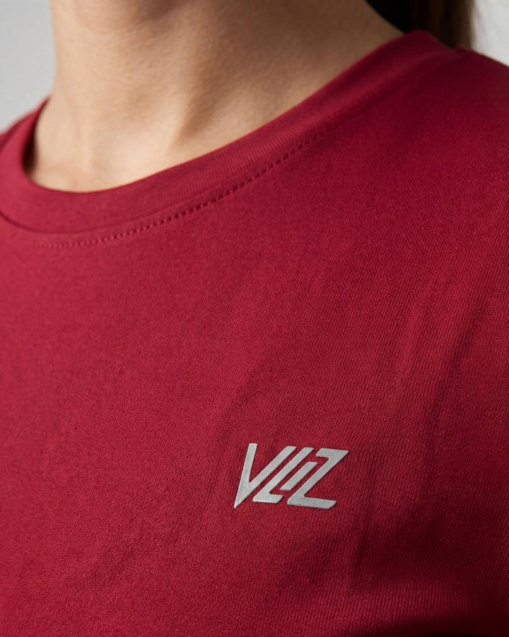 A model wears a form-fitting, short-sleeved deep red crew neck t-shirt. The smooth fabric highlights a comfortable, athletic fit suitable for workouts or casual wear.