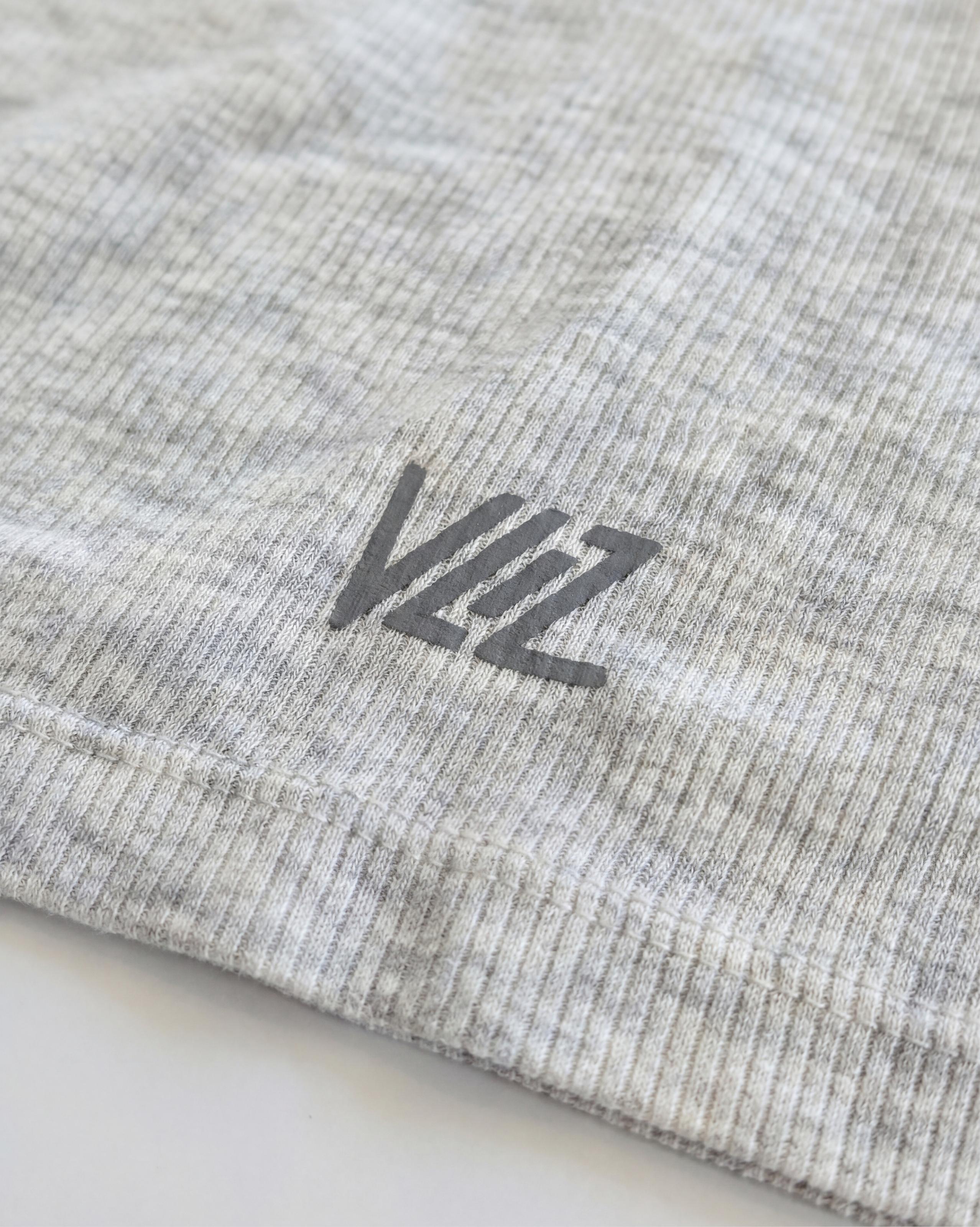 VLIZ Soft-Ribbed Padded Tank Top; a blonde woman models a light grey ribbed tank top with built-in pads and a supportive racerback design, paired with black leggings against a white background. Ideal for gym workouts, yoga, Pilates, and everyday training, highlighting its comfortable, flattering fit.