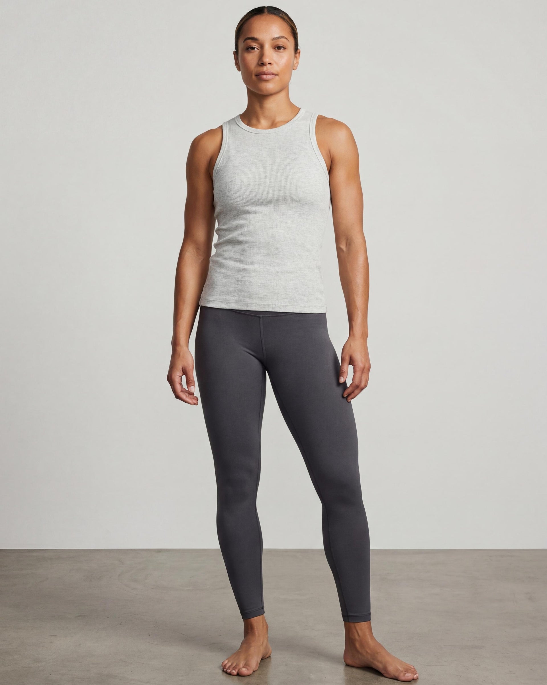 VLIZ Soft-Ribbed Padded Tank Top; a blonde woman models a light grey ribbed tank top with built-in pads and a supportive racerback design, paired with black leggings against a white background. Ideal for gym workouts, yoga, Pilates, and everyday training, highlighting its comfortable, flattering fit.