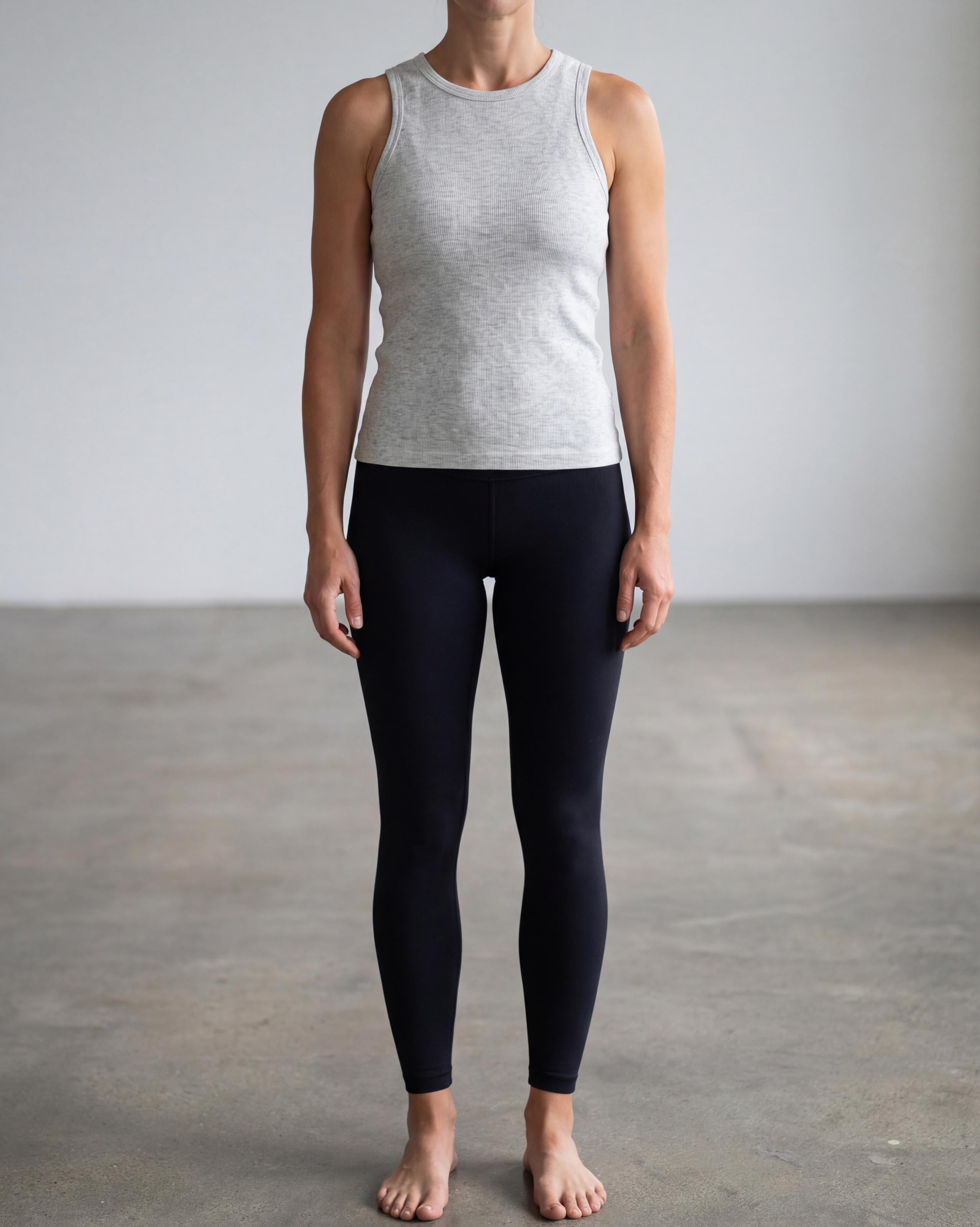 VLIZ Soft-Ribbed Padded Tank Top; a blonde woman models a light grey ribbed tank top with built-in pads and a supportive racerback design, paired with black leggings against a white background. Ideal for gym workouts, yoga, Pilates, and everyday training, highlighting its comfortable, flattering fit.