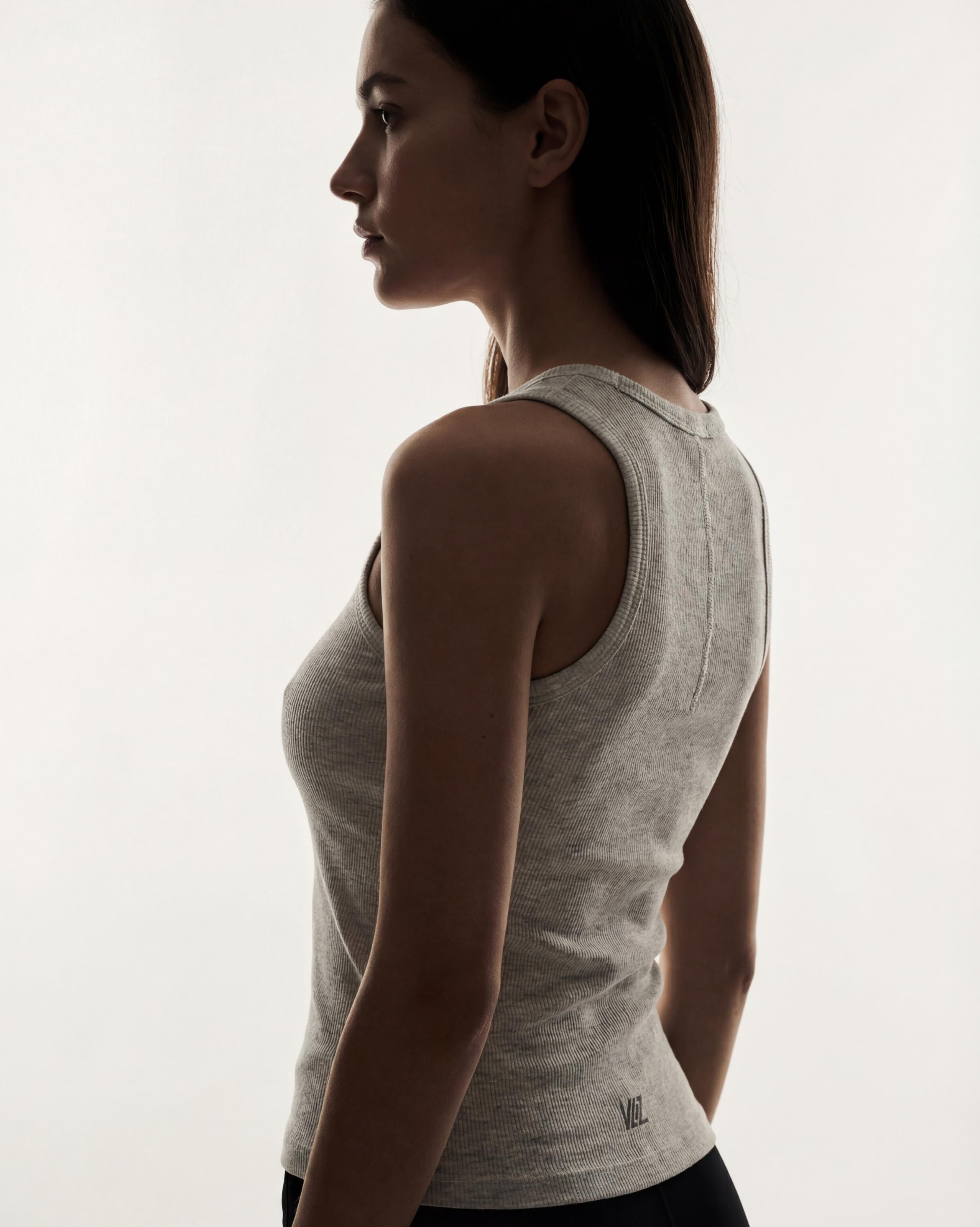 VLIZ Soft-Ribbed Padded Tank Top; a blonde woman models a light grey ribbed tank top with built-in pads and a supportive racerback design, paired with black leggings against a white background. Ideal for gym workouts, yoga, Pilates, and everyday training, highlighting its comfortable, flattering fit.