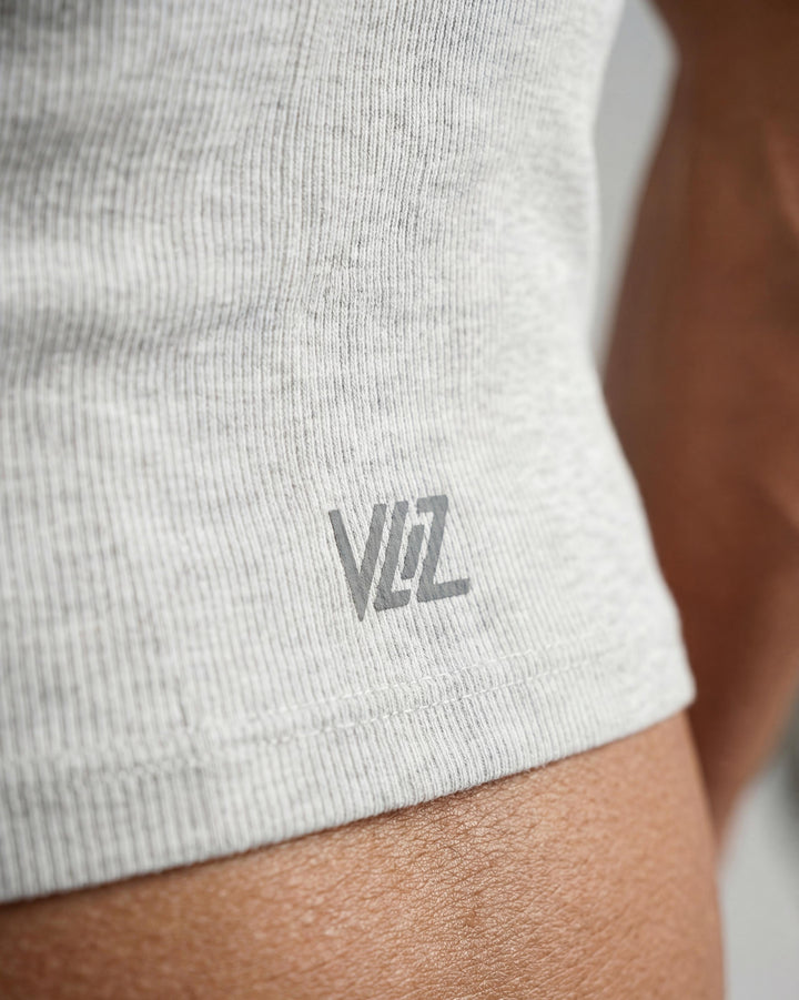 VLIZ Soft-Ribbed Padded Tank Top; a blonde woman models a light grey ribbed tank top with built-in pads and a supportive racerback design, paired with black leggings against a white background. Ideal for gym workouts, yoga, Pilates, and everyday training, highlighting its comfortable, flattering fit.
