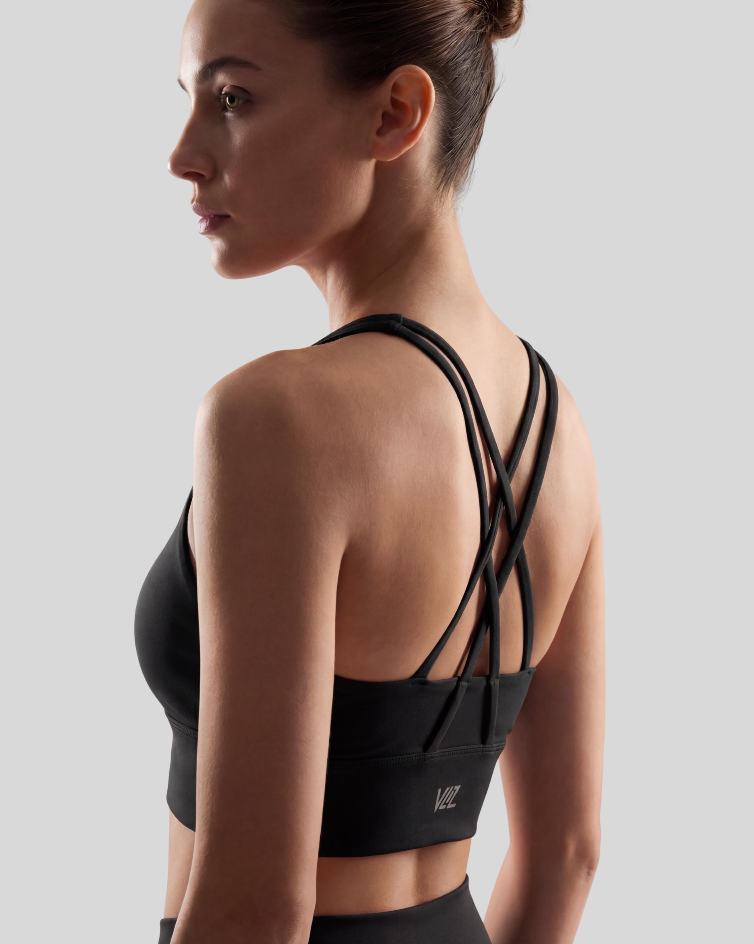 VLIZ Strappy-Back Sports Bra. A woman models the vibrant red/black sports bra with a high neckline and distinctive criss-cross back straps. The ribbed fabric provides a supportive fit, suitable for gym workouts, yoga, Pilates, and everyday training.