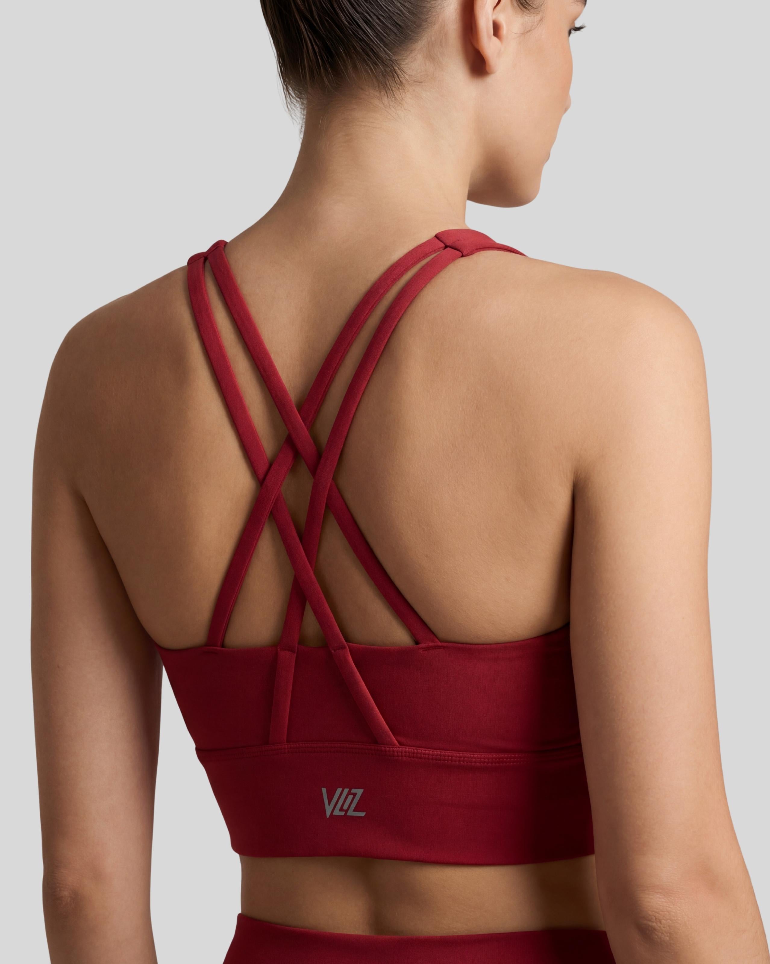 VLIZ Strappy-Back Sports Bra. A woman models the vibrant red/black sports bra with a high neckline and distinctive criss-cross back straps. The ribbed fabric provides a supportive fit, suitable for gym workouts, yoga, Pilates, and everyday training.