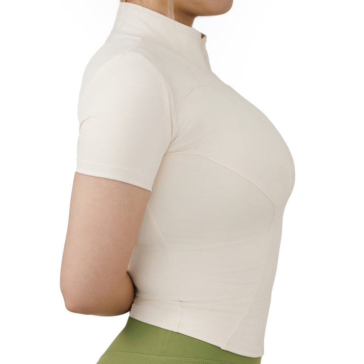 Side view of VLIZ Full-Zip SculptFit Short Sleeve Top in White, showcasing the sculpted seams, cropped silhouette, and mock neck design.