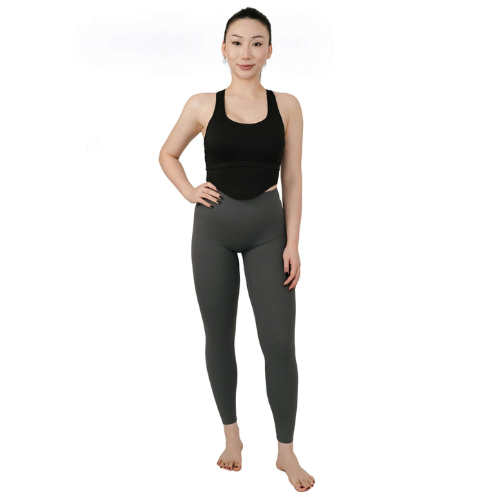 Full-body front view of VLIZ SculptFit Racerback Sports Bra in black, highlighting the sculpting fit and high neckline, styled with grey leggings.

