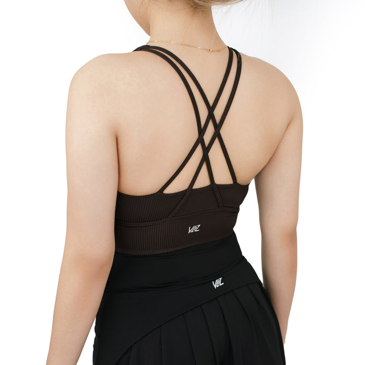 Back view of VLIZ ContourFlex Cross-Back Sports Bra in dark brown with criss-cross straps, paired with a pleated black athletic skirt