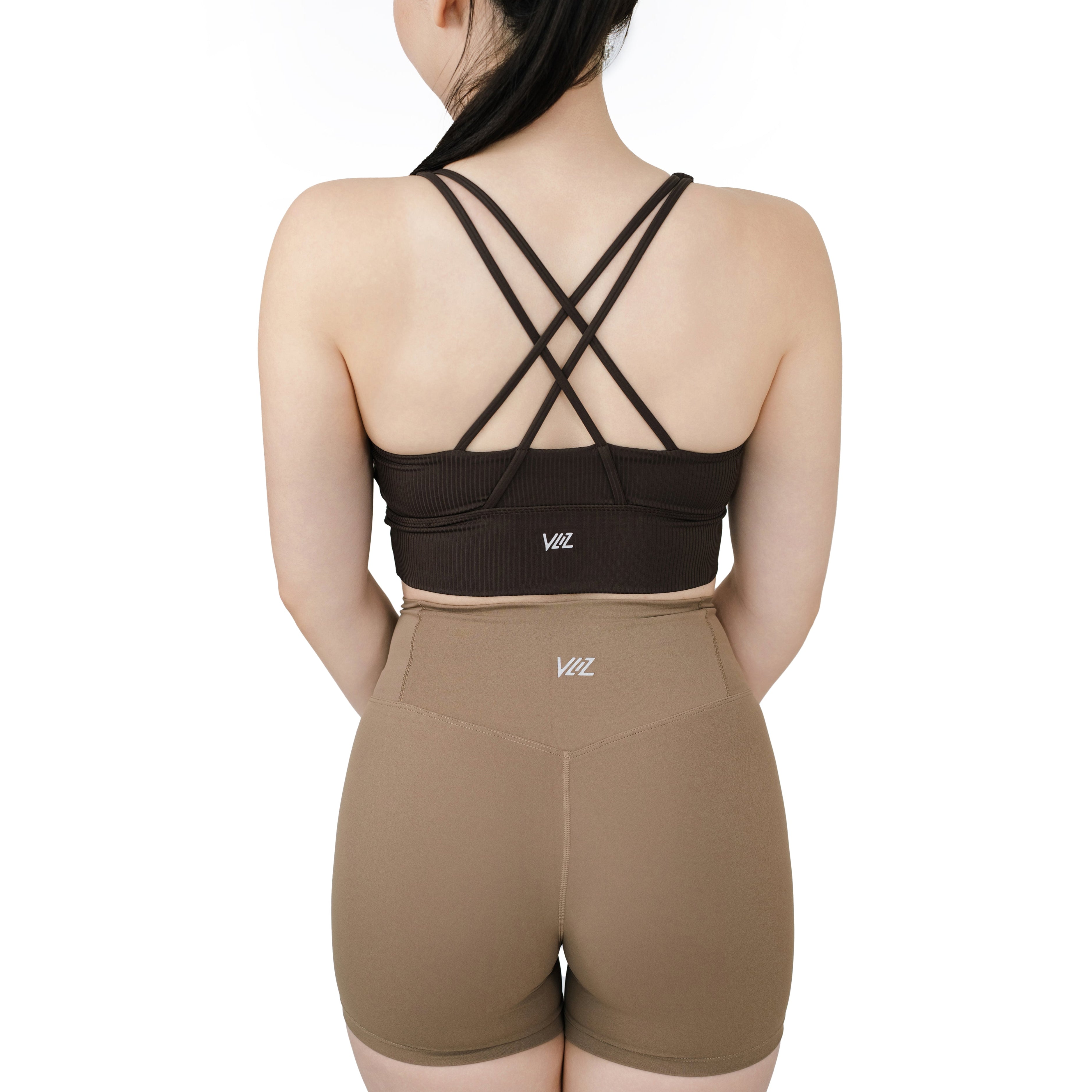 Model wearing VLIZ ContourFlex Cross-Back Sports Bra in dark brown (espresso), showcasing the criss-cross back strap detail.