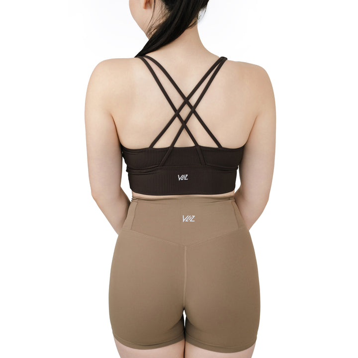 Model wearing VLIZ ContourFlex Cross-Back Sports Bra in dark brown (espresso), showcasing the criss-cross back strap detail.