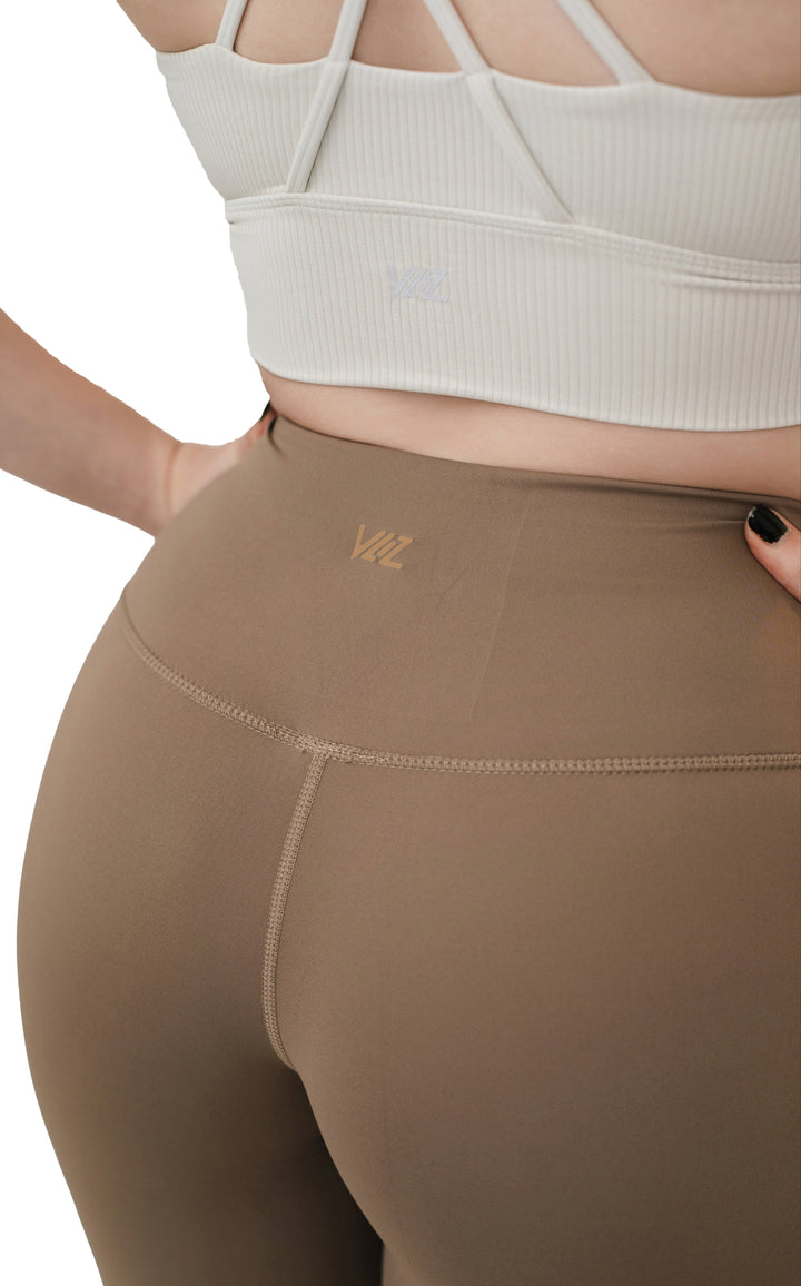 Close-up of the back detail on the VLIZ ContourFlex Cross-Back Sports Bra in white, showcasing the criss-cross straps and subtle logo on ribbed fabric for a supportive and stylish look.