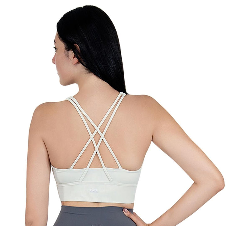 Model in VLIZ ContourFlex Cross-Back Sports Bra in White, featuring criss-cross back straps and a sculpting, supportive fit ideal for yoga, Pilates, cardio, tennis, and everyday active movement.