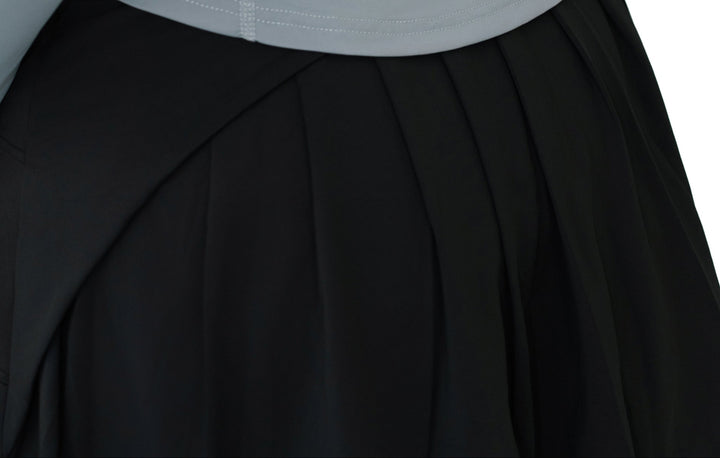 Close-up of the pleated back design on VLIZ ContourFlex Tennis Skirt in black, showing angled seam and waistline detail,