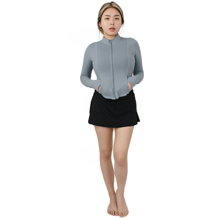 Full body view of model wearing VLIZ ContourFlex High-Waist Tennis Skirt in black, paired with a light zip-up top.