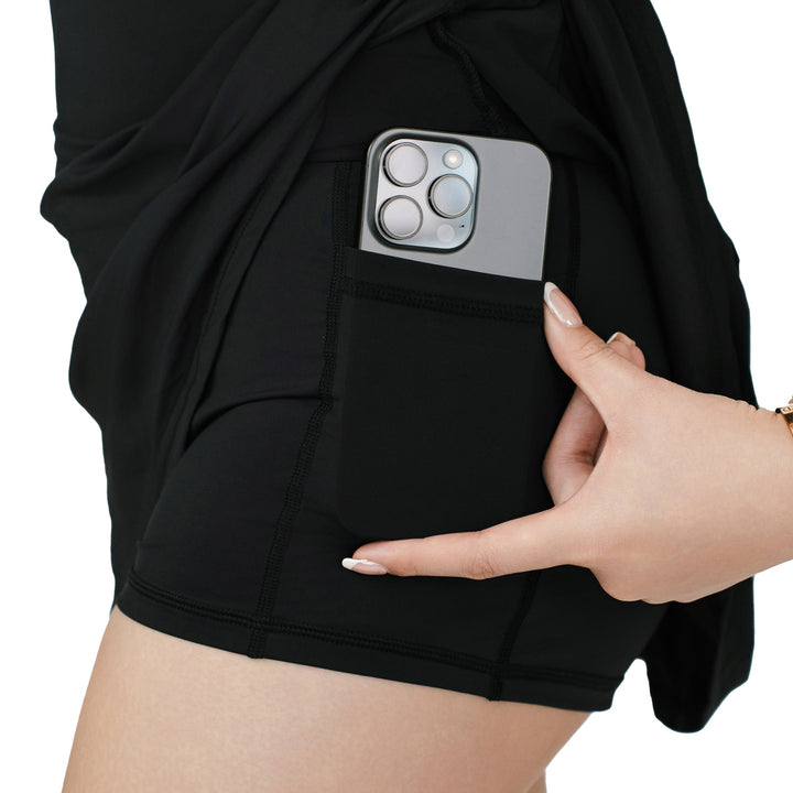 Close-up of VLIZ ContourFlex Tennis Skirt in black, showing hidden inner shorts with pocket holding a phone.