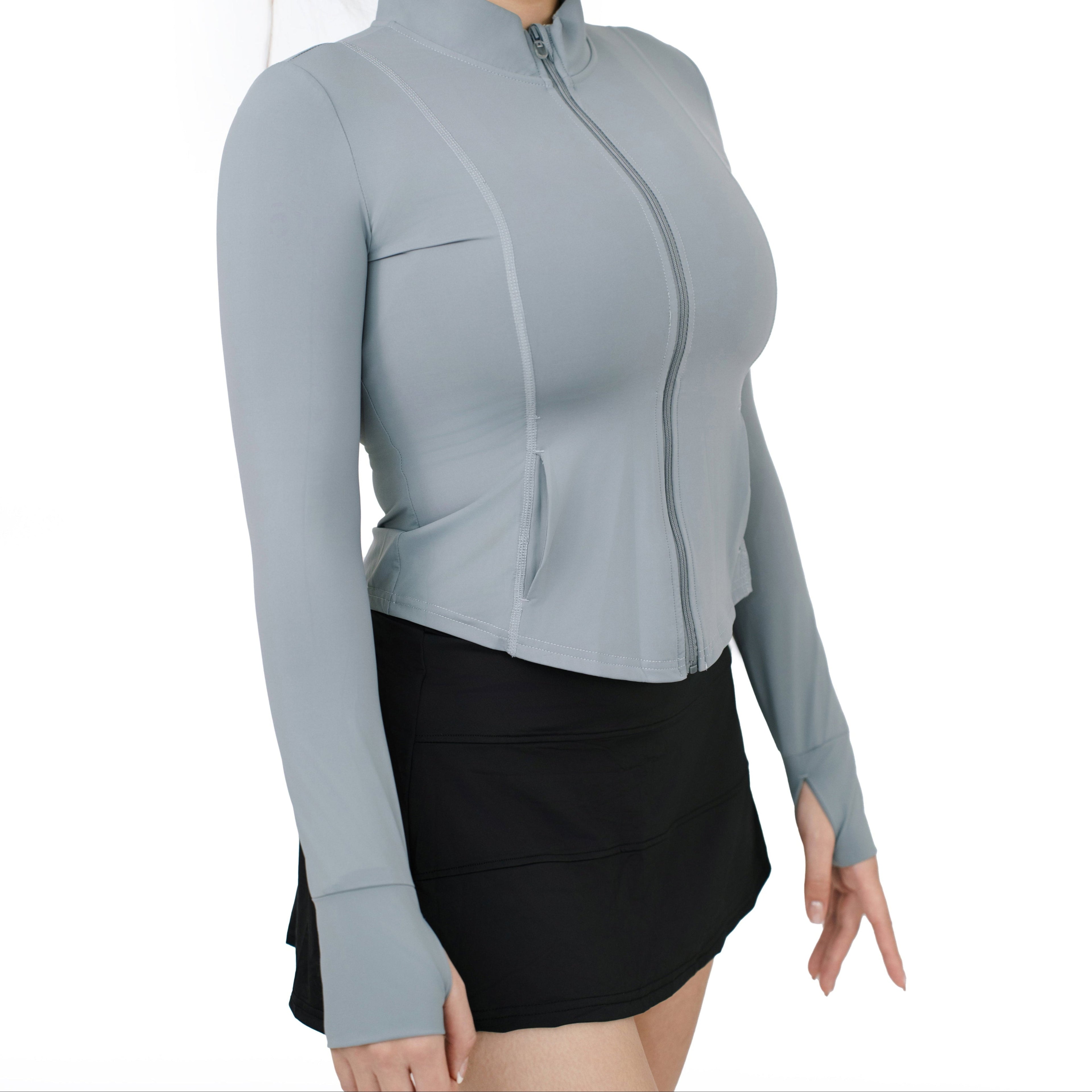 Side angle view of model wearing VLIZ ContourFlex High-Waist Tennis Skirt in black, styled with a light long-sleeve zip-up top.