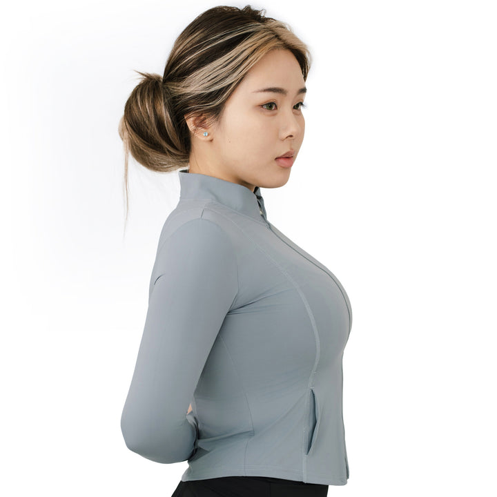 Model in VLIZ ash gray zip-up SlimFit top shown in side profile, highlighting curved seamlines and stand collar design.