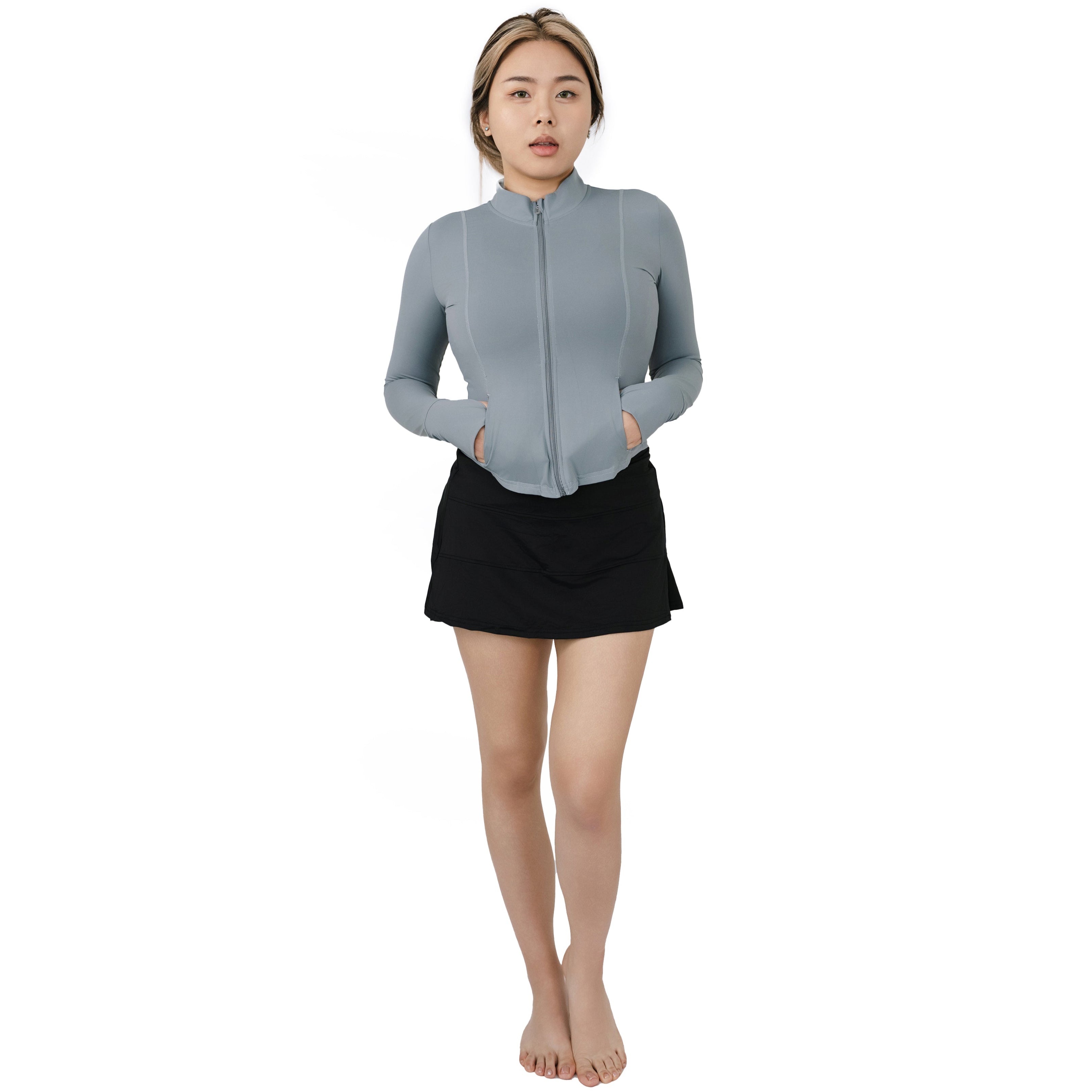 Model wearing VLIZ ash gray full-zip SlimFit top and black skirt, shown in full body front view with hands in pockets and high-neck design.