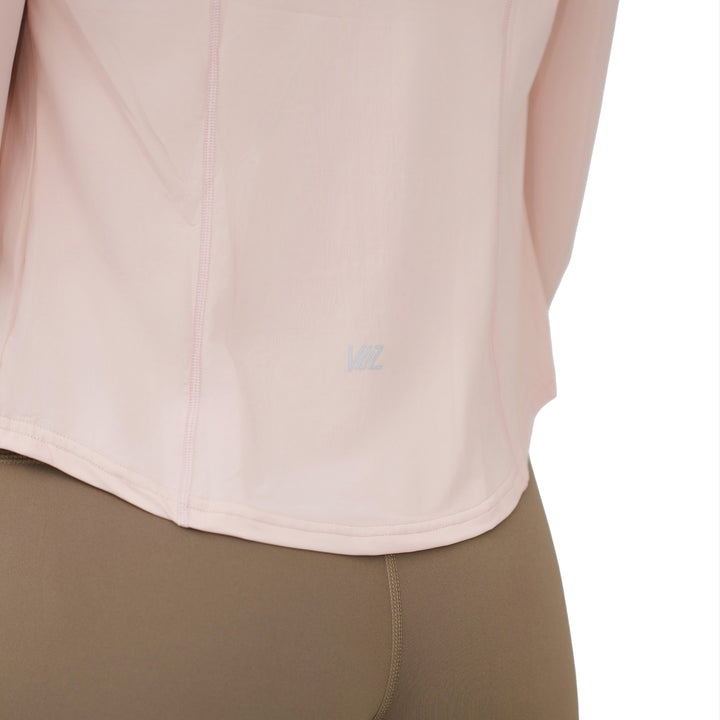 Close-up of VLIZ logo on the back hem of the peach pink SlimFit top, showing fabric texture and stitching detail.