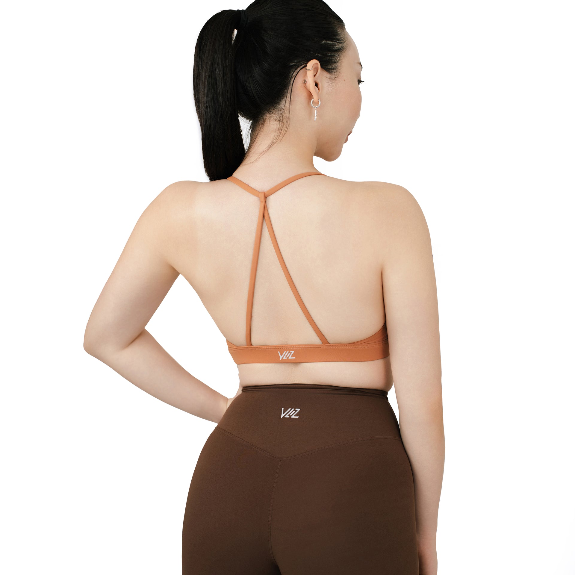 Back view of the VLIZ SculptFlex Cross-Back Sports Bra in Caramel Orange, featuring a minimalist Y-shaped strap design and elastic underband for support.