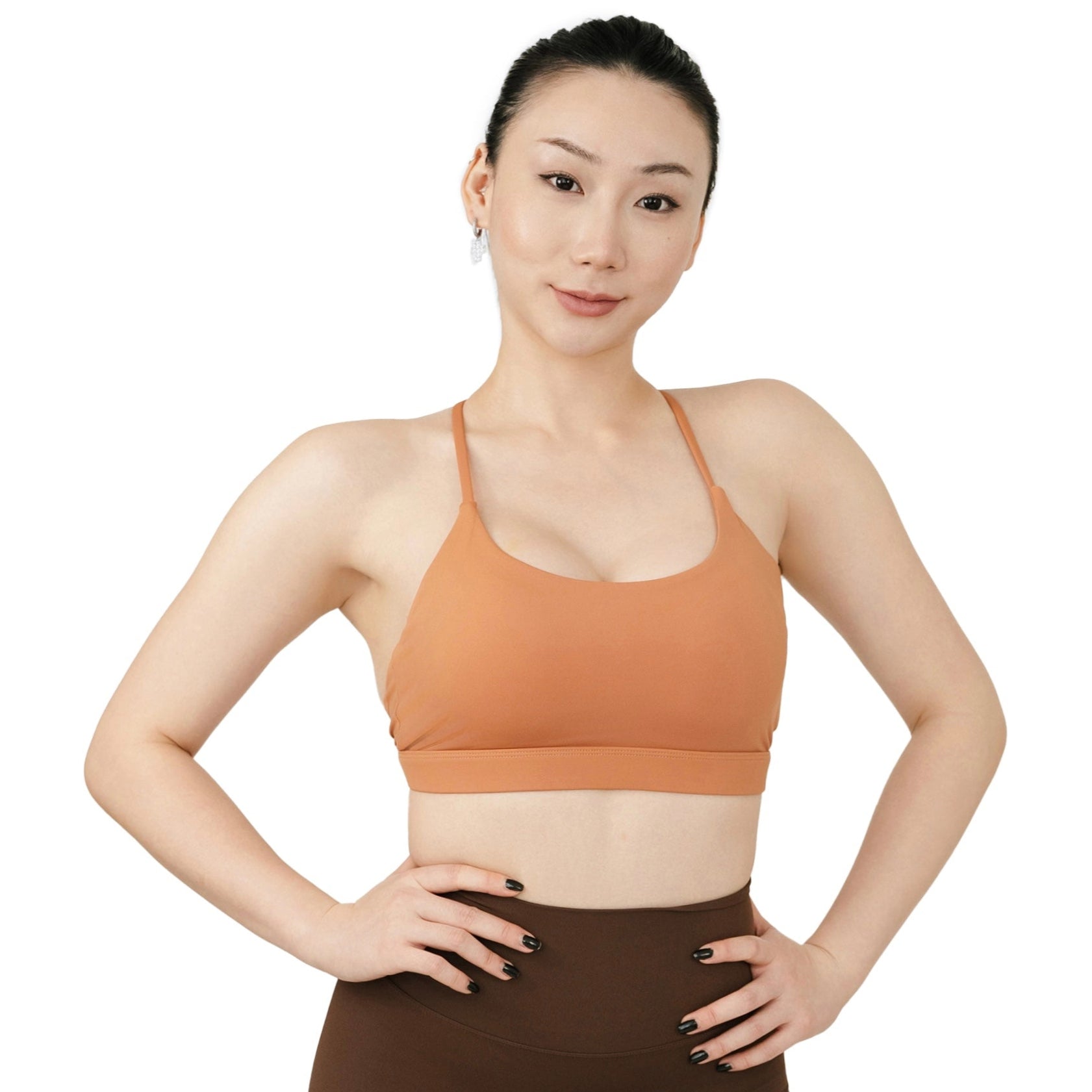 Front view of the VLIZ SculptFlex Cross-Back Sports Bra in Caramel Orange, featuring a scoop neckline and sleek, supportive fit, ideally for yoga, gym, and lifestyle layering.