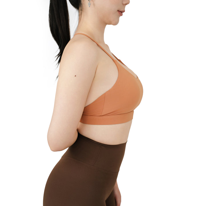 Side view of the VLIZ SculptFlex Cross-Back Sports Bra in Caramel Orange, highlighting the sleek straps, smooth side panel, and supportive underband fit.








