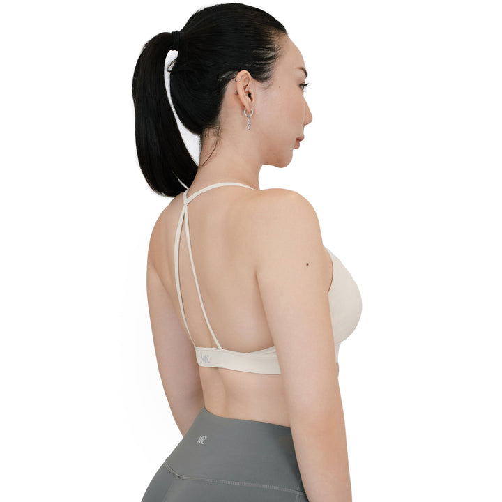 Angled back view of the VLIZ SculptFlex Sports Bra in White, featuring minimalist cross-back spaghetti straps and a low scoop back for breathable support during workouts.