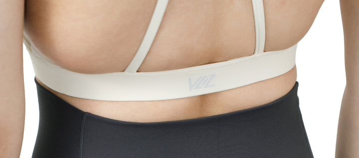 Detailed view of the VLIZ SculptFlex Cross-Back Sports Bra in White, showing the back straps and centered VLIZ logo printed on the elastic underband.