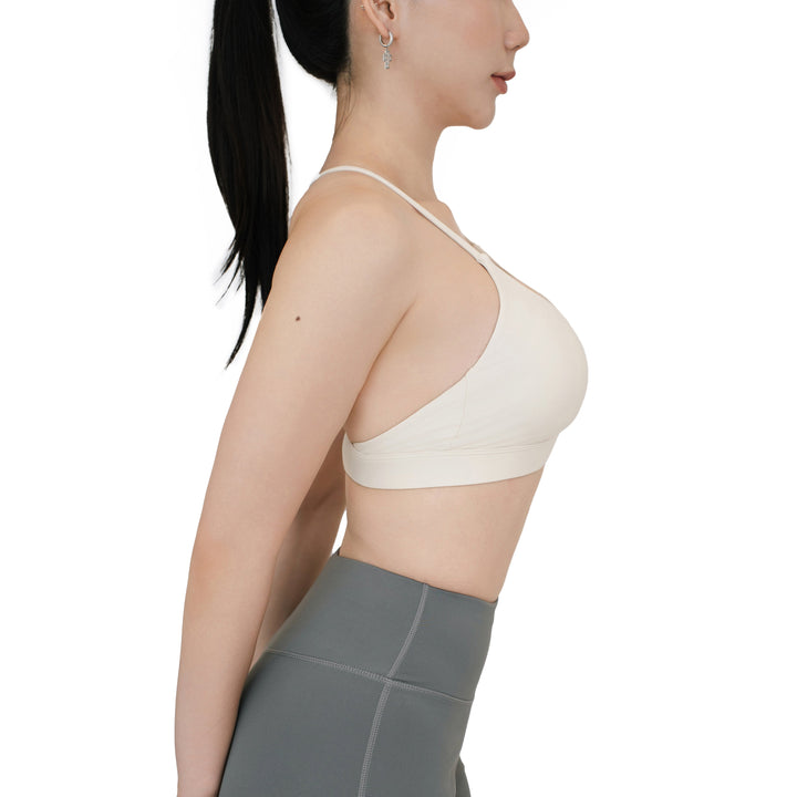 Side view of the VLIZ SculptFlex Sports Bra in White, showing sleek spaghetti straps, a scoop neckline, and smooth nylon construction designed for both comfort and support.