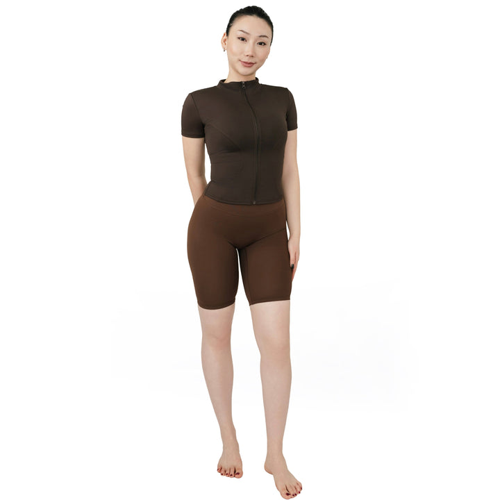 VLIZ Ultra Soft SculptFit Mid-Length Legging Shorts in chestnut brown, shown in a full front view with high waist and above-the-knee fit. Paired with a matching fitted zip-up activewear top.