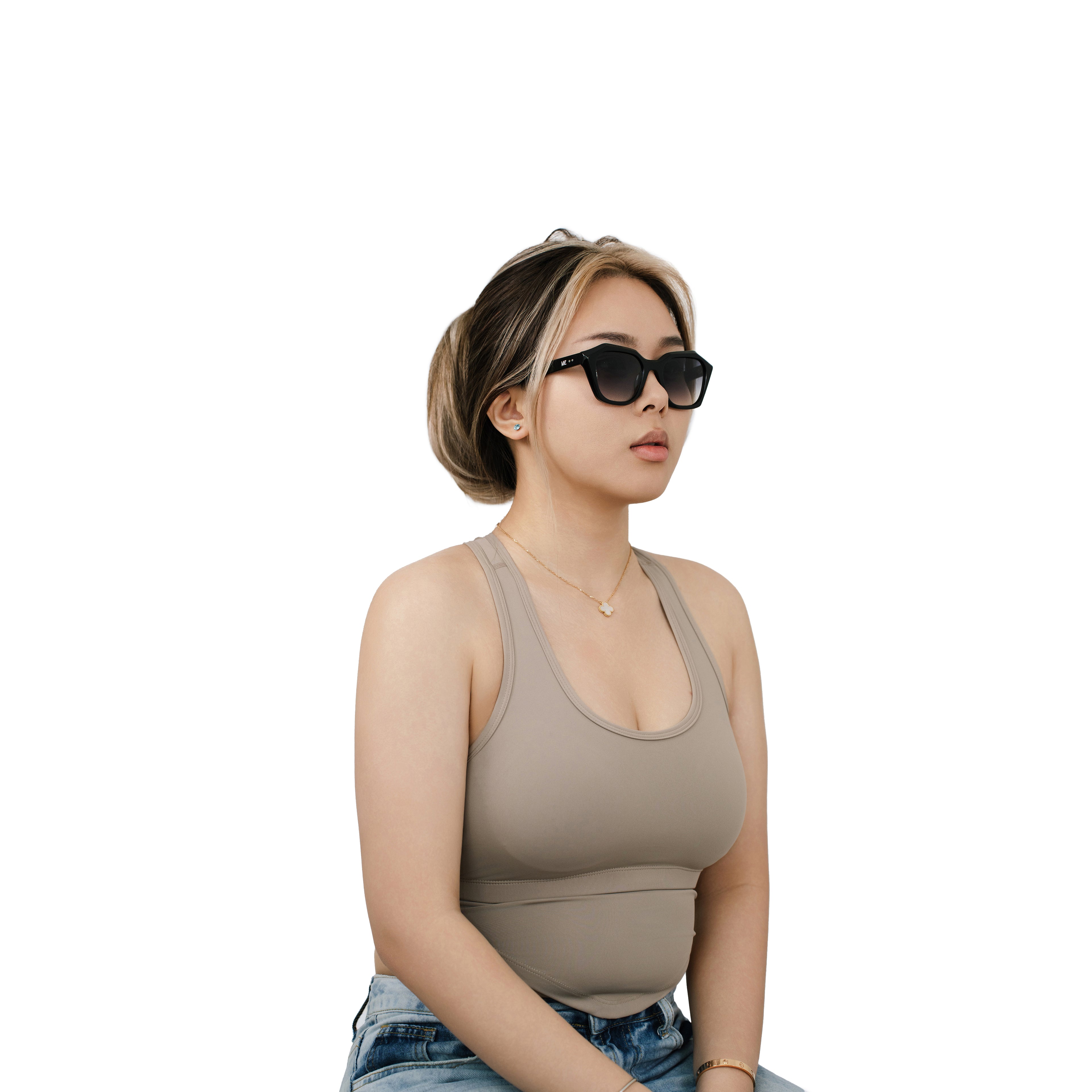 Model wearing VLIZ Altara sunglasses with a black square-oval frame and grey lenses, styled in a taupe sports tank and denim jeans, capturing a cool, casual, UV-protected look.
