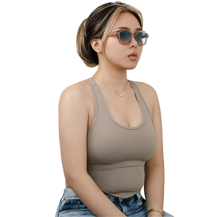 Model wearing VLIZ Altara sunglasses with a translucent pink-gradient frame and blue lenses, paired with a taupe sports tank and denim jeans, showing a soft yet modern unisex aesthetic with UV400 lens protection.