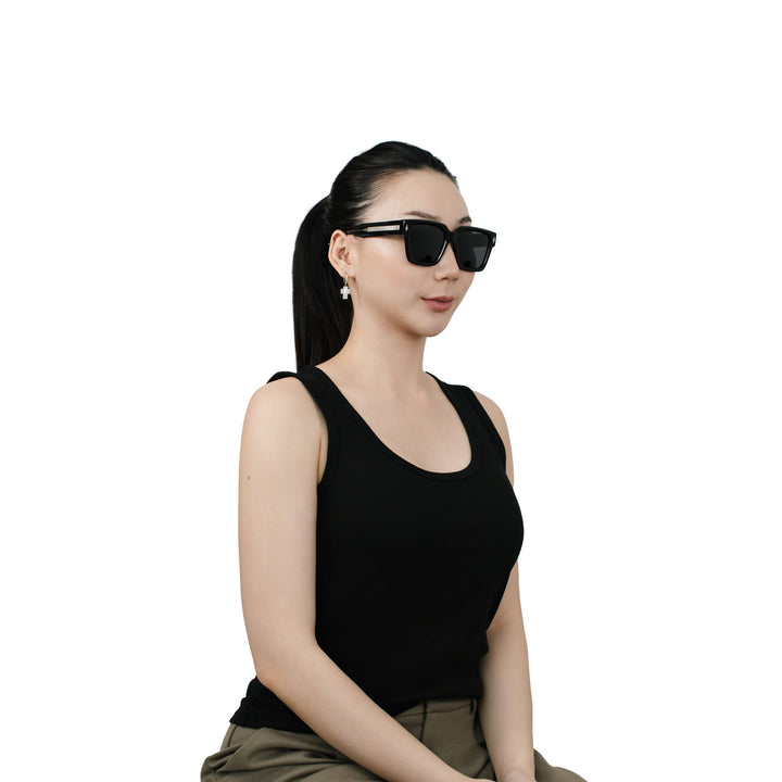 Model wearing VLIZ Gravité black square sunglasses with silver-tone temples and dark UV400 lenses, styled with a sleek ponytail and black tank top, showcasing the unisex street-luxury look.