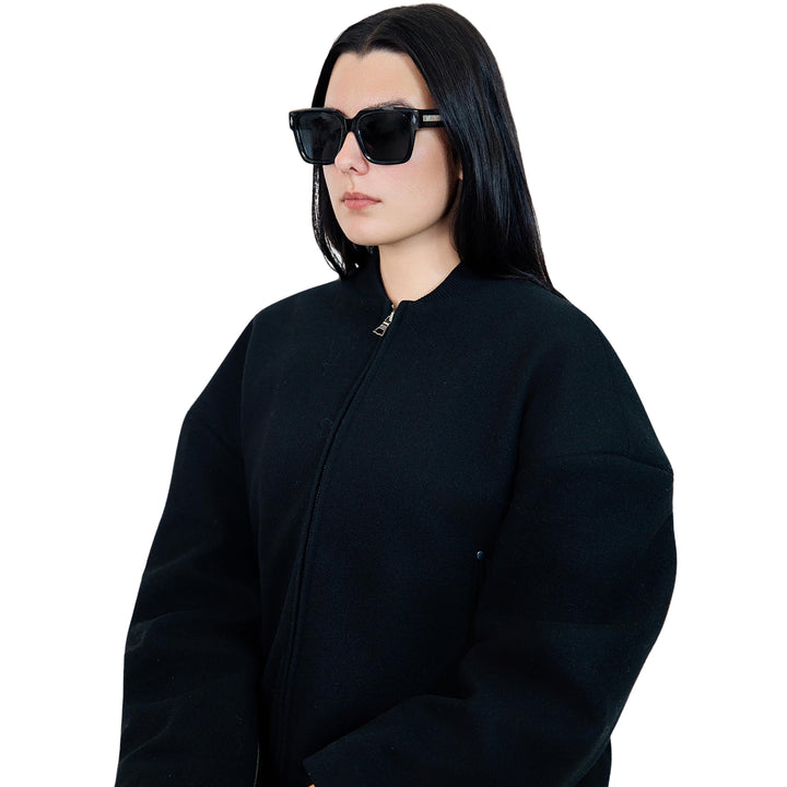 Model wearing VLIZ Gravité black square sunglasses with silver-tone temples and UV400 lenses, paired with a layered hoodie and graphic tee for an effortlessly cool streetwear look.