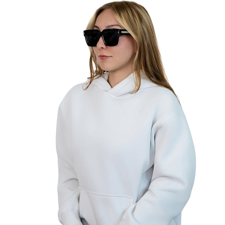 Model wearing VLIZ Gravité black square sunglasses with silver-tone temples and UV400 lenses, paired with a layered hoodie and graphic tee for an effortlessly cool streetwear look.