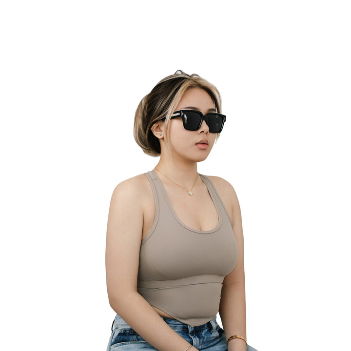 Model wearing VLIZ Gravité black square sunglasses with silver-tone temples and dark UV400 lenses, styled in a taupe racerback top and jeans, highlighting the modern unisex appeal of the design.