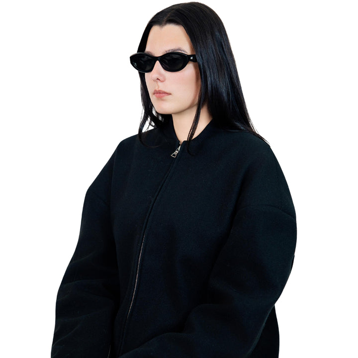 VLIZ Nolita oval sunglasses with black frame and black lenses, featuring smooth oval design and engraved logo on temples.
