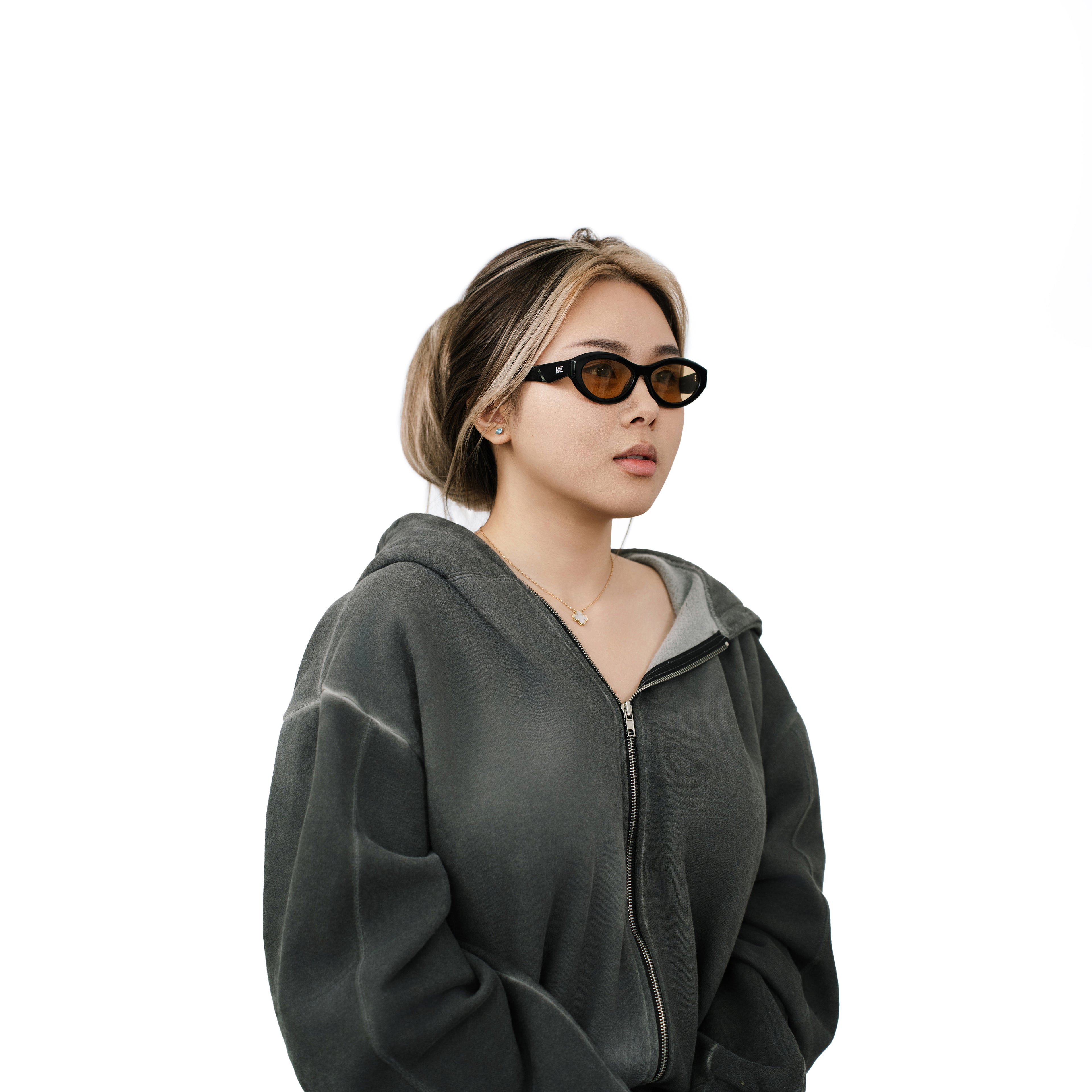 VLIZ Nolita oval sunglasses with black frame and brown lenses, featuring smooth oval design and engraved logo on temples.
