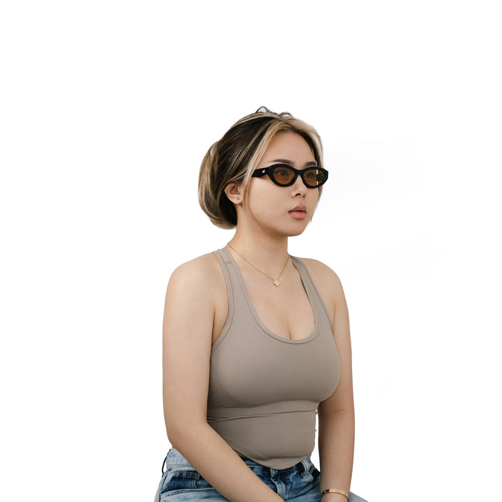VLIZ Nolita oval sunglasses with black frame and brown lenses, featuring smooth oval design and engraved logo on temples.
