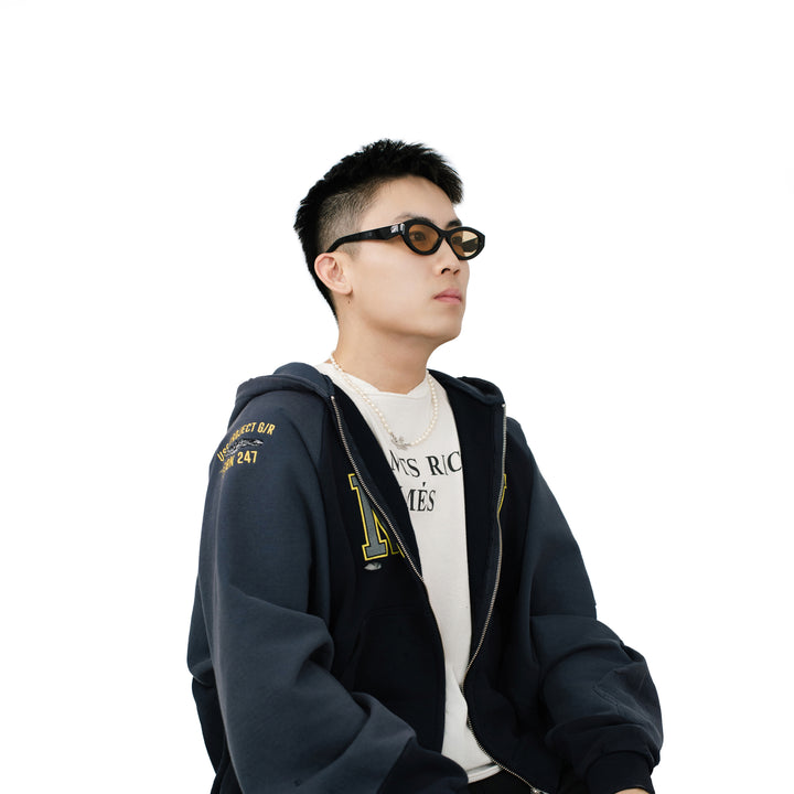 VLIZ Nolita oval sunglasses with black frame and brown lenses, featuring smooth oval design and engraved logo on temples.