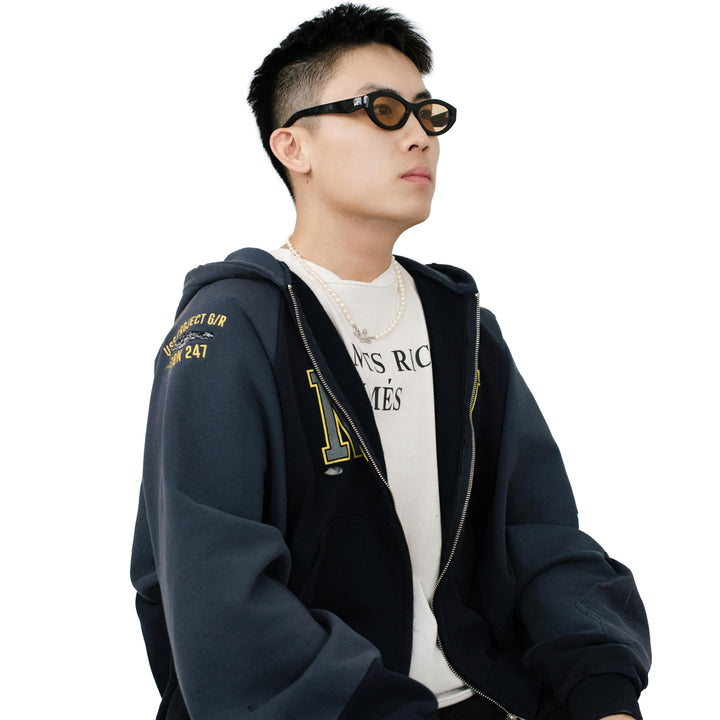 VLIZ Nolita oval sunglasses with black frame and brown lenses, featuring smooth oval design and engraved logo on temples.