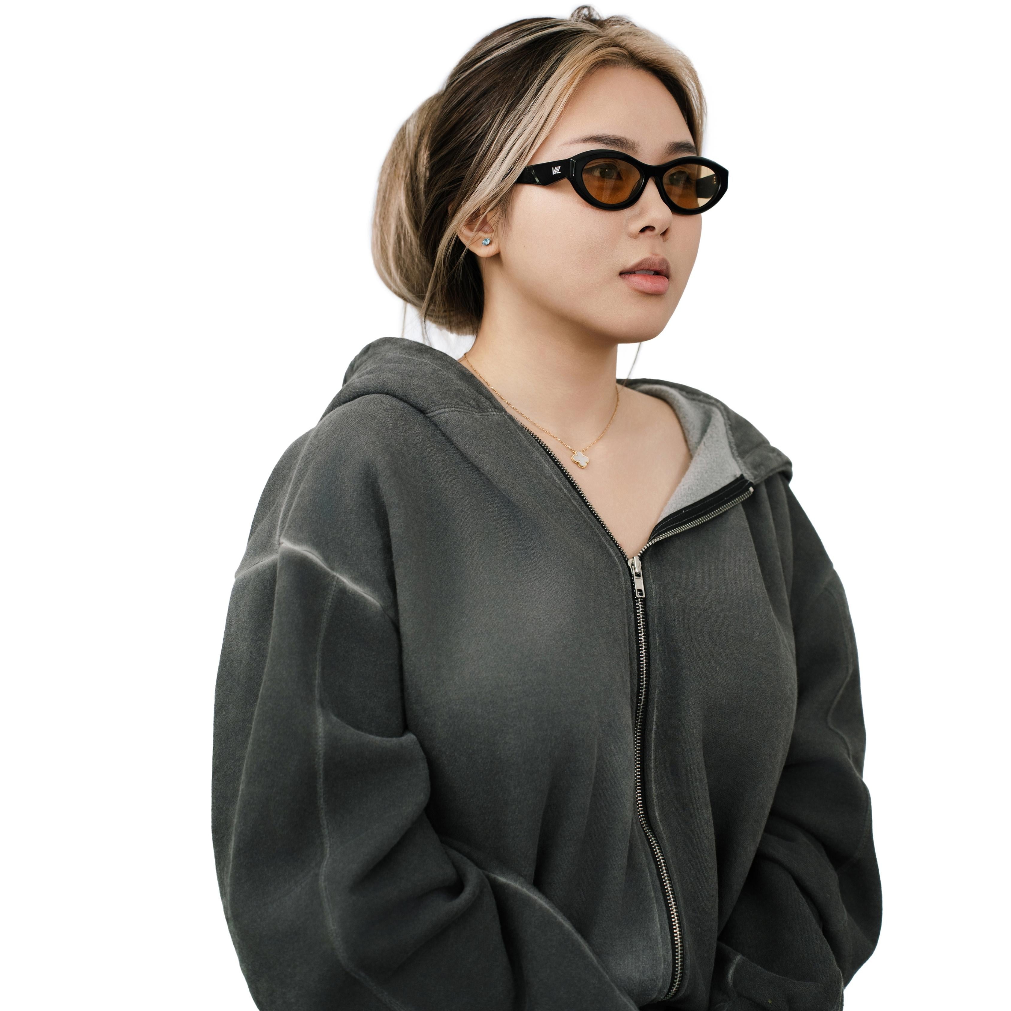 VLIZ Nolita oval sunglasses with black frame and brown lenses, featuring smooth oval design and engraved logo on temples.